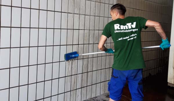 Eine Person in Arbeitskleidung reinigt Fliesen mit einer Bürste in Hoyerswerda