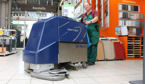 Eine Person bedient eine blaue Bodenreinigungsmaschine.