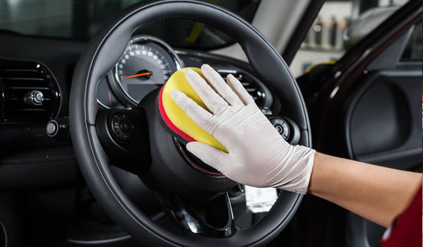 Eine Hand mit einem Handschuh reinigt ein Lenkrad in Hoyerswerda